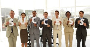 Business people holding letters spelling success