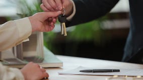 Business, real estate, deal and people concept - man giving house keys to woman at office. stock video Business, real estate, deal and people concept - man giving house keys to woman at office. stock video