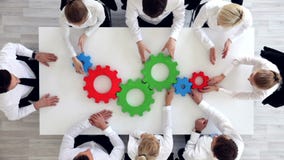 Business team with cogs. Business team sitting around the table with cogs, teamwork concept Business team with cogs. Business team sitting around the table with cogs, teamwork concept