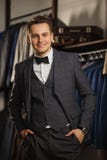 Businessman in classic vest against row of suits in shop. A young stylish man in a black cloth jacket. It is in the showroom, tryi royalty free stock photo Businessman in classic vest against row of suits in shop. A young stylish man in a black cloth jacket. It is in the showroom, tryi royalty free stock photo
