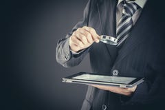Businessman Holding Magnifying Glass And Digital Tablet On Dark Background, Searching And Examining Concept Businessman Holding Magnifying Glass And Digital Tablet On Dark Background, Searching And Examining Concept