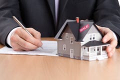 Businessman signs contract behind house architectu royalty free stock photography Businessman signs contract behind house architectu royalty free stock photography