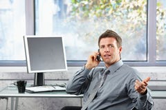 Businessman speaking on mobile at desk stock photo Businessman speaking on mobile at desk stock photo