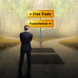 Businessman standing at a crossroad having to decide between `free trade ` and `protectionism ` stock photos Businessman standing at a crossroad having to decide between `free trade ` and `protectionism ` stock photos