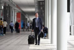Businessman walking with trolley through the crowd on a business travel Stock Photos Businessman walking with trolley through the crowd on a business travel Stock Photos
