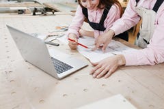 Businesswoman carpenter working on laptop on wooden surface among construction tools. Nearby is smartphone, laptop ,clipboard. stock image Businesswoman carpenter working on laptop on wooden surface among construction tools. Nearby is smartphone, laptop ,clipboard. stock image