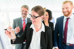 Businesswoman writes on a flipboard in front of three co-workers Royalty Free Stock Photo Businesswoman writes on a flipboard in front of three co-workers Royalty Free Stock Photo