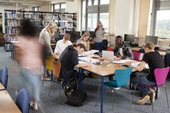 Busy College Library With Teacher Helping Students At Table royalty free stock images Busy College Library With Teacher Helping Students At Table royalty free stock images