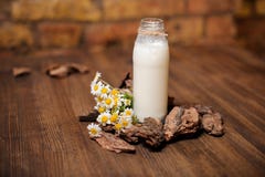 Butelka wieśniaka mleko i bukiet chamomile na drewnianym stole zdjęcie stock Butelka wieśniaka mleko i bukiet chamomile na drewnianym stole zdjęcie stock