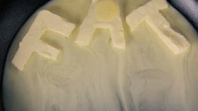 Butter in shape of the word fat melting on hot pan - Close up top view