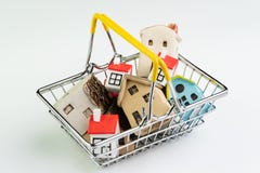 Buy and sell house or real estate purchasing concept, shopping basket with full of small cute miniature houses on white background