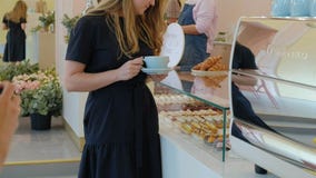 She buyer chooses yummy. Young attractive girl, woman buys in the coffee shop or pastries, cakes, cake, macaroon. A stock footage She buyer chooses yummy. Young attractive girl, woman buys in the coffee shop or pastries, cakes, cake, macaroon. A stock footage