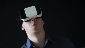 Bärande virtuell verklighetskyddsglasögon för man studioskott, svart bakgrund långsam rörelse arkivfilmer Bärande virtuell verklighetskyddsglasögon för man studioskott, svart bakgrund långsam rörelse arkivfilmer