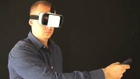 Bärande virtuell verklighetskyddsglasögon för man studioskott, svart bakgrund långsam rörelse stock video Bärande virtuell verklighetskyddsglasögon för man studioskott, svart bakgrund långsam rörelse stock video