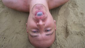 Bästa sikt av den unga mannen som blåser upp bubblor som ligger på stranden stock video Bästa sikt av den unga mannen som blåser upp bubblor som ligger på stranden stock video