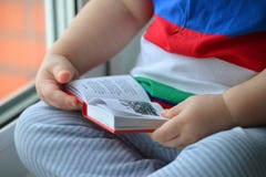 Bébé garçon lisant un livre, dclose des mains poussant des feuilles par les pages image libre de droits Bébé garçon lisant un livre, dclose des mains poussant des feuilles par les pages image libre de droits