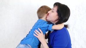 Bébé heureux étreignant sa maman s'asseyant sur un sofa blanc Le concept d'une famille heureuse banque de vidéos Bébé heureux étreignant sa maman s'asseyant sur un sofa blanc Le concept d'une famille heureuse banque de vidéos