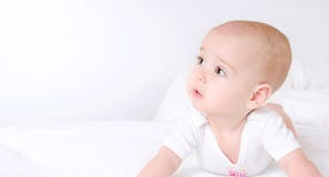 Bébé mignon avec de beaux yeux bruns se situant dans le lit blanc image libre de droits Bébé mignon avec de beaux yeux bruns se situant dans le lit blanc image libre de droits