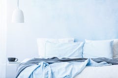 Błękitne poduszki na łóżku obok stołu z filiżanki und i bedsheets zdjęcie stock Błękitne poduszki na łóżku obok stołu z filiżanki und i bedsheets zdjęcie stock