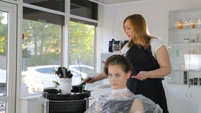 Cabeleireiro profissional, estilista que colore o cabelo adolescente da menina video estoque Cabeleireiro profissional, estilista que colore o cabelo adolescente da menina video estoque