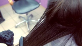 Cabelo marrom escuro dos straights do cabeleireiro da mulher bonita que usa tenazes de brasa do cabelo no salão de beleza Close-u video estoque Cabelo marrom escuro dos straights do cabeleireiro da mulher bonita que usa tenazes de brasa do cabelo no salão de beleza Close-u video estoque