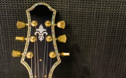 Cabeça bonita da guitarra com os botões giratórios dourados e o embutimento decorativo isolados em um fundo do amplificador da mú fotografia de stock Cabeça bonita da guitarra com os botões giratórios dourados e o embutimento decorativo isolados em um fundo do amplificador da mú fotografia de stock