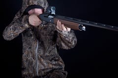 Cacciatore in abbigliamento del cammuffamento con una pistola su un fondo nero isolato L'uomo con il fucile da caccia Giovane tip immagini stock libere da diritti Cacciatore in abbigliamento del cammuffamento con una pistola su un fondo nero isolato L'uomo con il fucile da caccia Giovane tip immagini stock libere da diritti