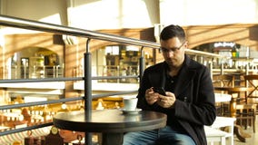 Caffè bevente del maschio adulto con un telefono in sua mano in caffè stock footage Caffè bevente del maschio adulto con un telefono in sua mano in caffè stock footage