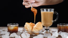 Caffè con i croissant deliziosi sulla lastra di vetro Caramello liquido puro caldo che piove a dirotto sul dessert al rallentator stock footage Caffè con i croissant deliziosi sulla lastra di vetro Caramello liquido puro caldo che piove a dirotto sul dessert al rallentator stock footage