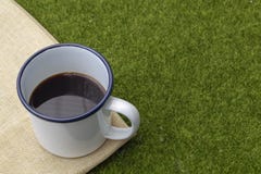 Caffè in tazza bianca della latta sul fondo dell'erba fotografie stock libere da diritti Caffè in tazza bianca della latta sul fondo dell'erba fotografie stock libere da diritti