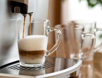 Café de cappuccino préparant dans la tasse en verre avec la machine images stock Café de cappuccino préparant dans la tasse en verre avec la machine images stock