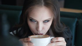 Café de consumición de la muchacha morena hermosa en un restaurante Disfruta de gusto y del aroma almacen de metraje de vídeo Café de consumición de la muchacha morena hermosa en un restaurante Disfruta de gusto y del aroma almacen de metraje de vídeo