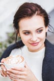 Café de consumición del capuchino de la mujer morena hermosa con espuma en el café de la calle foto de archivo libre de regalías Café de consumición del capuchino de la mujer morena hermosa con espuma en el café de la calle foto de archivo libre de regalías