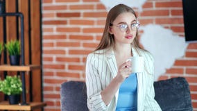 Café de pensamiento y de consumición de la mujer de negocios sonriente adorable en el tiro medio de la oficina moderna del desván almacen de metraje de vídeo Café de pensamiento y de consumición de la mujer de negocios sonriente adorable en el tiro medio de la oficina moderna del desván almacen de metraje de vídeo