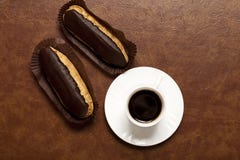 Café, Eclair de chocolat, café dans une tasse blanche, soucoupe blanche, sur une table brune, Eclair sur le support de papier photo stock Café, Eclair de chocolat, café dans une tasse blanche, soucoupe blanche, sur une table brune, Eclair sur le support de papier photo stock