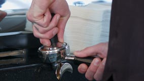 Café à terra das imprensas de Barista usando a calcadeira Café à terra das imprensas de Barista usando a calcadeira