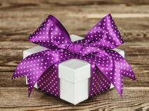 Caixa de presente branca com uma curva violeta na placa idosa fotos de stock Caixa de presente branca com uma curva violeta na placa idosa fotos de stock