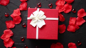 Caja de regalo en la tabla de piedra negra Fondo romántico del día de fiesta con los pétalos color de rosa Caja de regalo en la tabla de piedra negra Fondo romántico del día de fiesta con los pétalos color de rosa