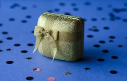 Caja del oro con la decoración como regalo en un fondo azul foto de archivo libre de regalías Caja del oro con la decoración como regalo en un fondo azul foto de archivo libre de regalías