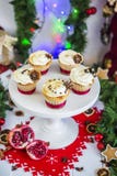 Cakes, cupcakes with dried lemon and chocolate on a white pedestal on a background of green Christmas garland and lights royalty free stock image Cakes, cupcakes with dried lemon and chocolate on a white pedestal on a background of green Christmas garland and lights royalty free stock image