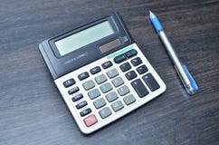 Calculadora com a pena no fundo de madeira da placa imagem de stock Calculadora com a pena no fundo de madeira da placa imagem de stock