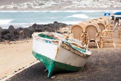 Caleta de Famara, Лансароте, Palmas/SPAIN - 2-ое февраля 2018: Рыбацкая лодка на берег и опорожняет внешний ресторан, с морем в t стоковые изображения Caleta de Famara, Лансароте, Palmas/SPAIN - 2-ое февраля 2018: Рыбацкая лодка на берег и опорожняет внешний ресторан, с морем в t стоковые изображения