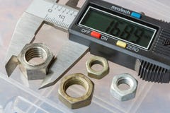 Calibro elettronico di Digital con i dadi utilizzati su un fondo della scatola di stoccaggio immagini stock Calibro elettronico di Digital con i dadi utilizzati su un fondo della scatola di stoccaggio immagini stock