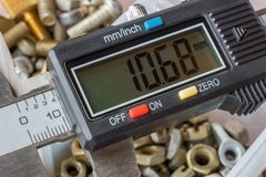 Calibro elettronico di Digital su un fondo della scatola di stoccaggio aperta con i bulloni utilizzati ed il primo piano matto immagine stock libera da diritti Calibro elettronico di Digital su un fondo della scatola di stoccaggio aperta con i bulloni utilizzati ed il primo piano matto immagine stock libera da diritti