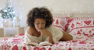 Calm beautiful African woman reading in bed stock footage Calm beautiful African woman reading in bed stock footage