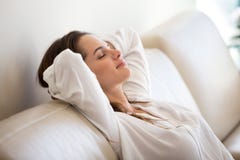 Calm millennial woman relaxing on comfortable sofa breathing fre