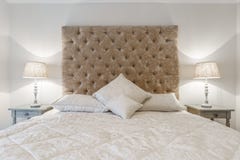 Cama cómoda grande con las lámparas de la noche en un dormitorio Fotos de archivo libres de regalías Cama cómoda grande con las lámparas de la noche en un dormitorio Fotos de archivo libres de regalías