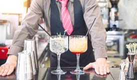 Camarero joven que hace los c?cteles en el contador de la barra - bebidas de servicio del camarero - trabajo, pasi?n y concepto d foto de archivo Camarero joven que hace los c?cteles en el contador de la barra - bebidas de servicio del camarero - trabajo, pasi?n y concepto d foto de archivo