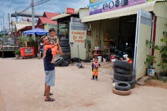 Cambodia, Siem Reap 12/08/2018 man with a child in his arms near the tire shop, slums of Asia, residents of poor areas of the stock photography Cambodia, Siem Reap 12/08/2018 man with a child in his arms near the tire shop, slums of Asia, residents of poor areas of the stock photography