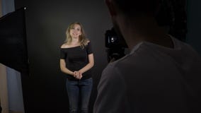 Cameraman joven que registra a una mujer hermosa joven atractiva que habla con la cámara para un nuevo episodio de su vlog video almacen de metraje de vídeo Cameraman joven que registra a una mujer hermosa joven atractiva que habla con la cámara para un nuevo episodio de su vlog video almacen de metraje de vídeo